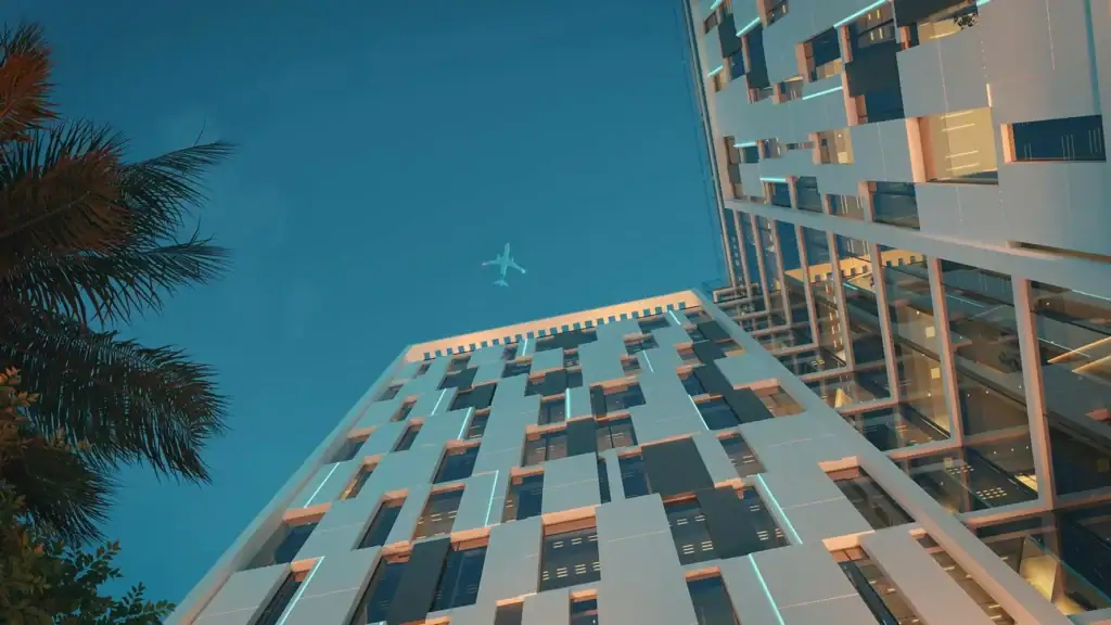 Modern high-rise building with glass facade and palm trees, clear blue sky.