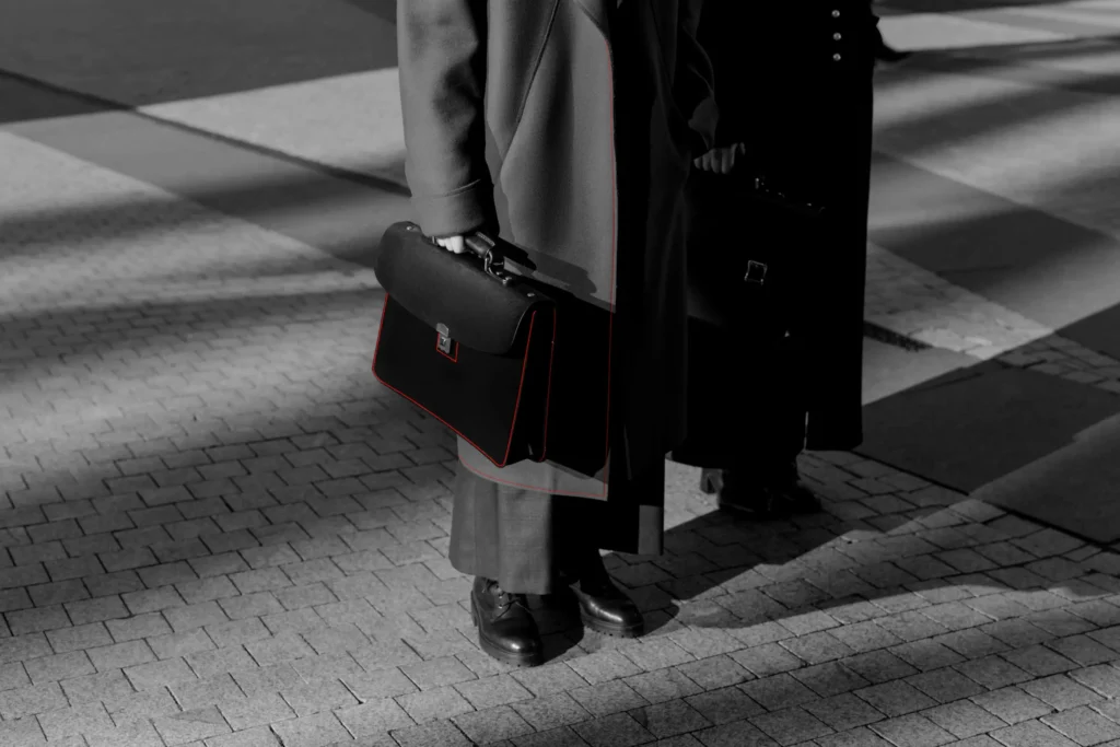 Business professional holding a briefcase at a crosswalk in black and white.